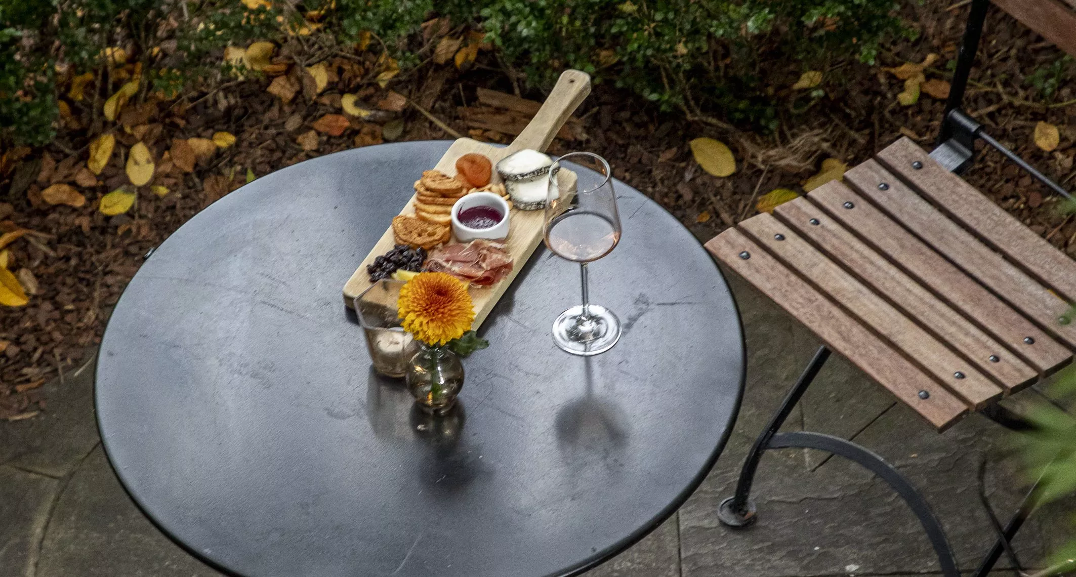 Charcuterie board with wine on table and bistro chair