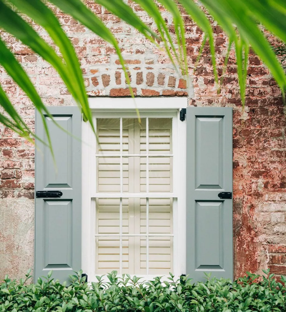 Brick building window with green shutters
