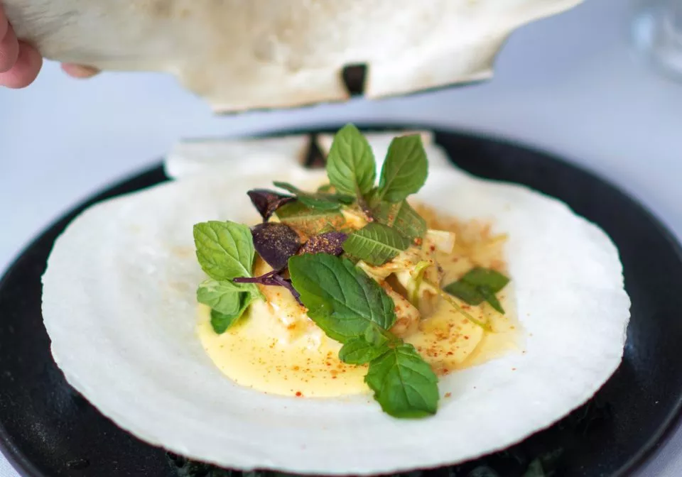 Close up of meal within a shell on a black plate