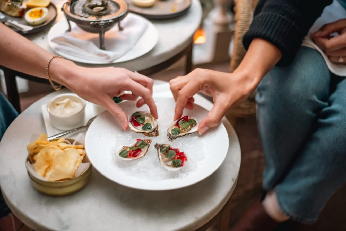 Guests enjoying freshly shucked oysters with vibrant garnishes at Zero George.