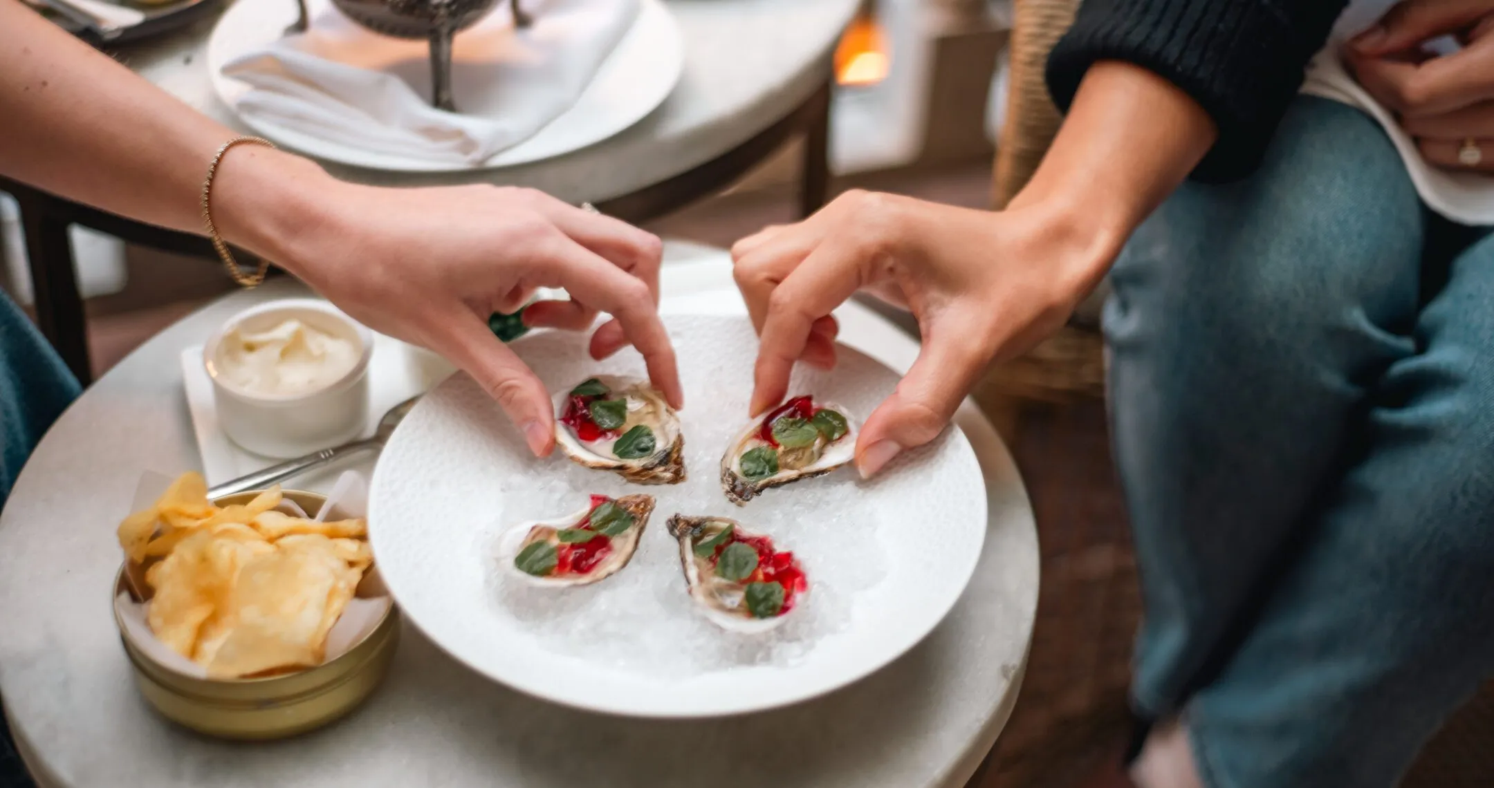 Guests enjoying freshly shucked oysters with vibrant garnishes at Zero George.