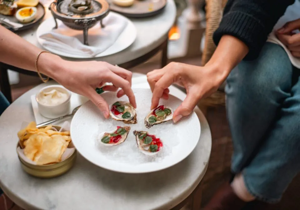 Guests enjoying freshly shucked oysters with vibrant garnishes at Zero George.